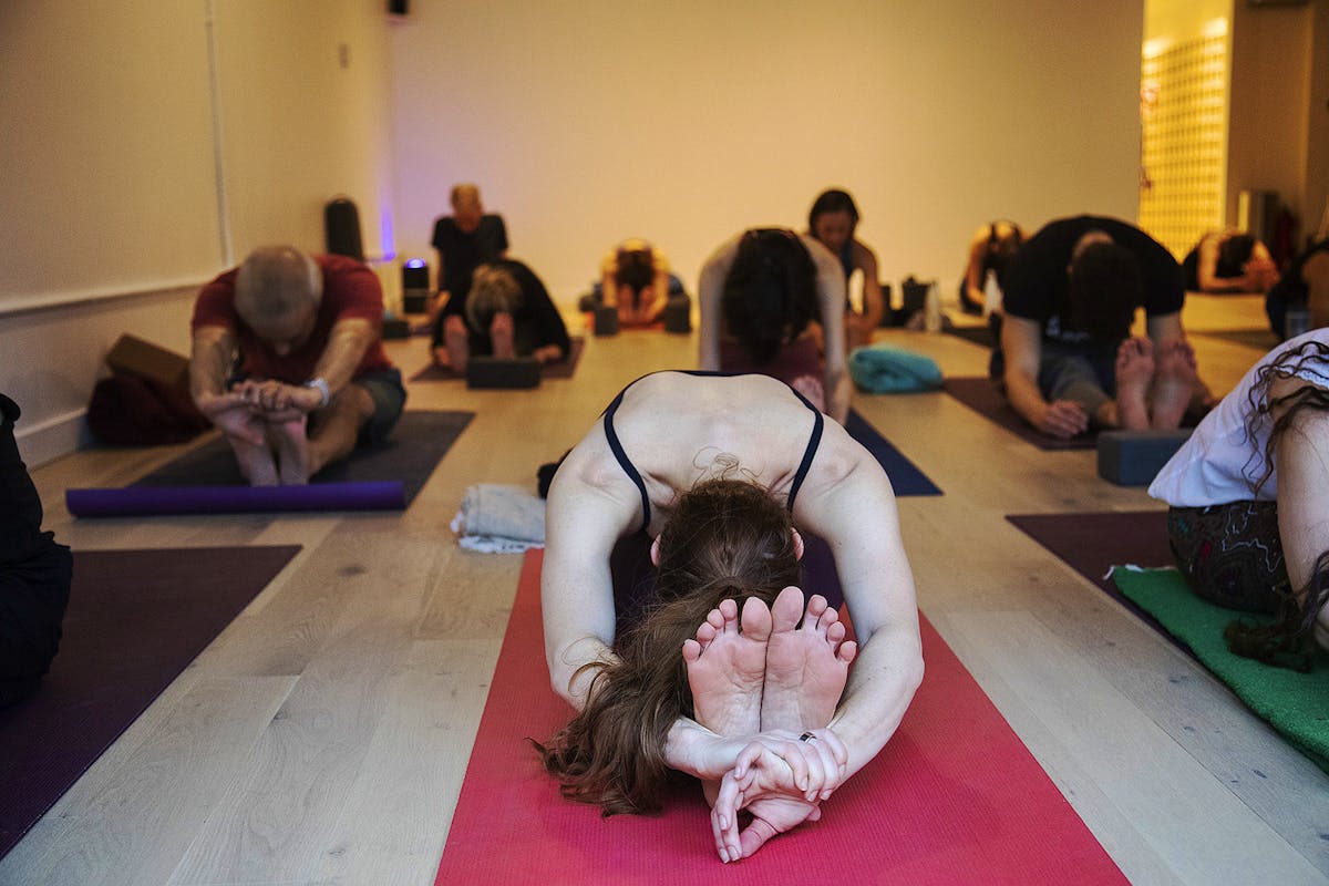 Students practicing full forward fold at the end of class. Credit: Abhaya Yoga.